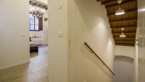 A staircase with wooden steps and a handrail, leading to a room with a radiator and a window.