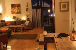 A living room with a sofa, coffee table, and a wooden table with various items. - Great View Guesthouse (Akureyri)