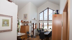 Un comedor amplio con una mesa y sillas de madera, una zona de cocina con armarios de madera y un ventanal con vistas.