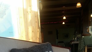 A cozy room with a sofa featuring a pillow with the text "Daeli". - Huts in Víðidalur (Hvammstangi)