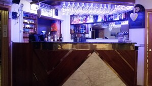 A bar area with a counter, shelves with bottles, and hanging glasses. - Huts in Víðidalur (Hvammstangi)