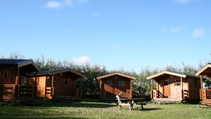 Three wooden cabins with a porch and a picnic table in front. - Huts in Víðidalur (Hvammstangi)