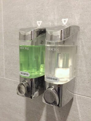 Two Mocha branded dispensers, one for shampoo and one for liquid soap, mounted on a tiled wall. - 1992 Capsule Hotel - Hostel (Malacca City)
