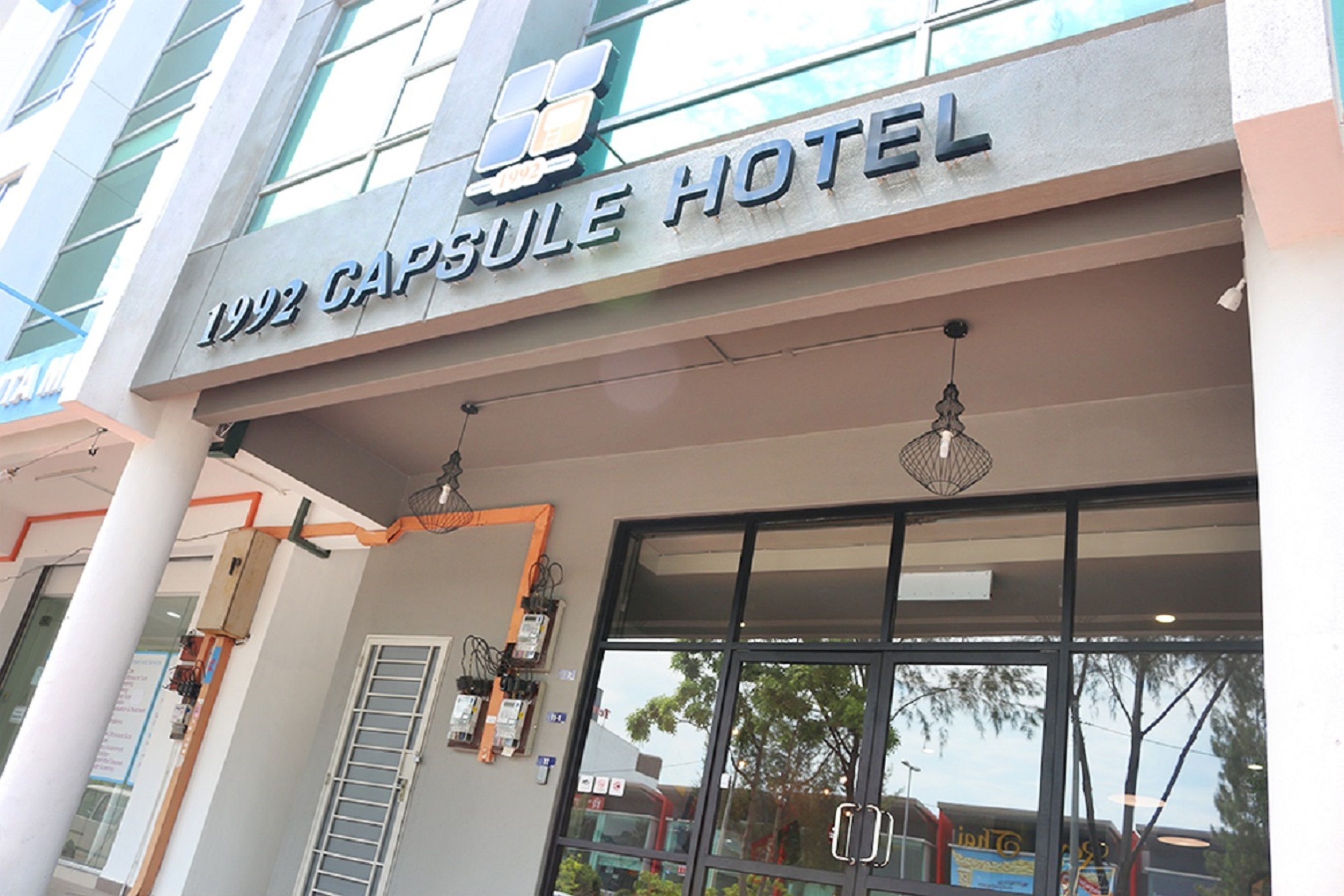 The exterior of the 1992 Capsule Hotel with a modern facade, large windows, and a visible entrance.