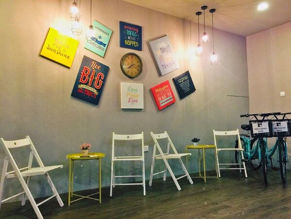 A room with white chairs, a clock, motivational posters, and a bicycle rack. - 1992 Capsule Hotel - Hostel (Malacca City)