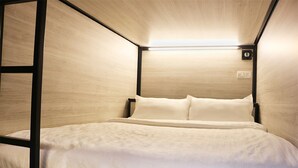 Habitación compacta con cama individual, detalles de madera y un diseño sencillo y limpio.