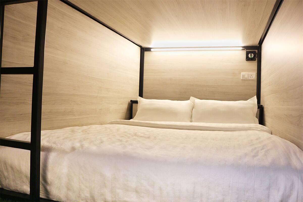 Habitación compacta con cama individual, detalles de madera y un diseño sencillo y limpio.