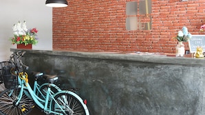 Zona de recepción con pared de ladrillo, mostrador de recepción y dos bicicletas estacionadas junto a la pared.