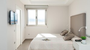 Une chambre à coucher avec un lit, une télévision, une fenêtre et une table de chevet avec une lampe.