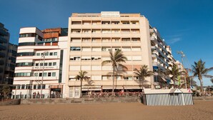 Un hôtel à plusieurs étages doté d’un atrium central, de balcons et situé en bord de mer.
