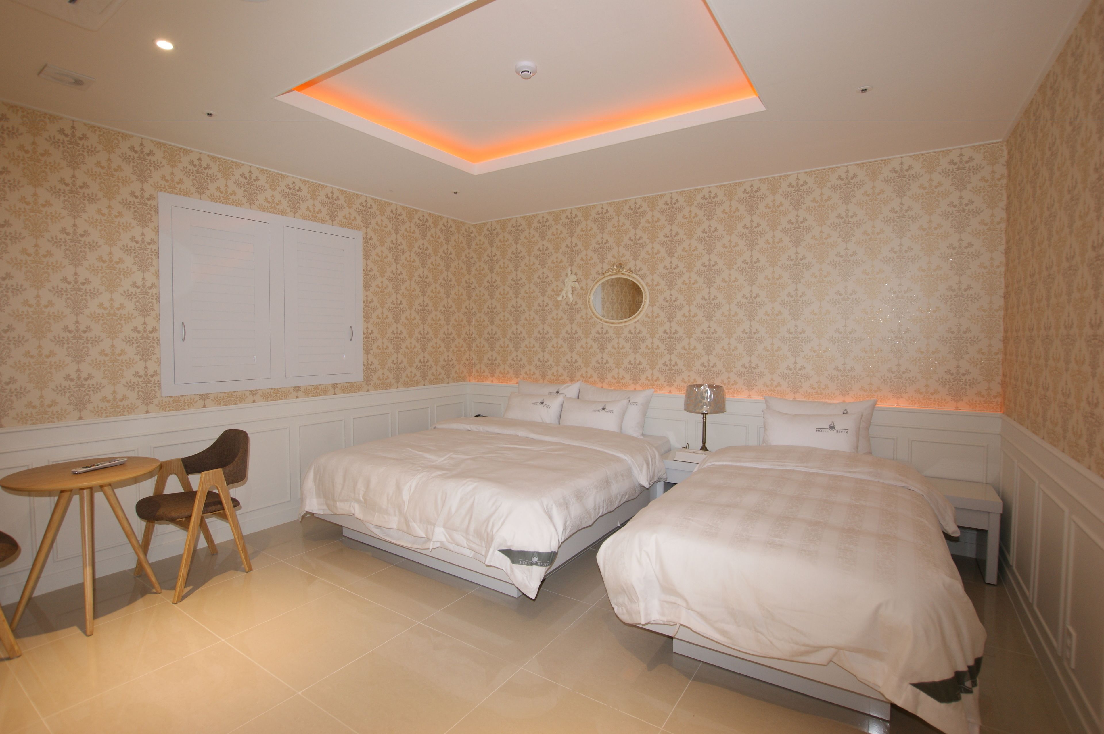 A bedroom with two beds, a small table, and a chair.