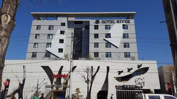Experience the Hotel River's sleek architectural design, featuring a prominent sign and central staircase.
