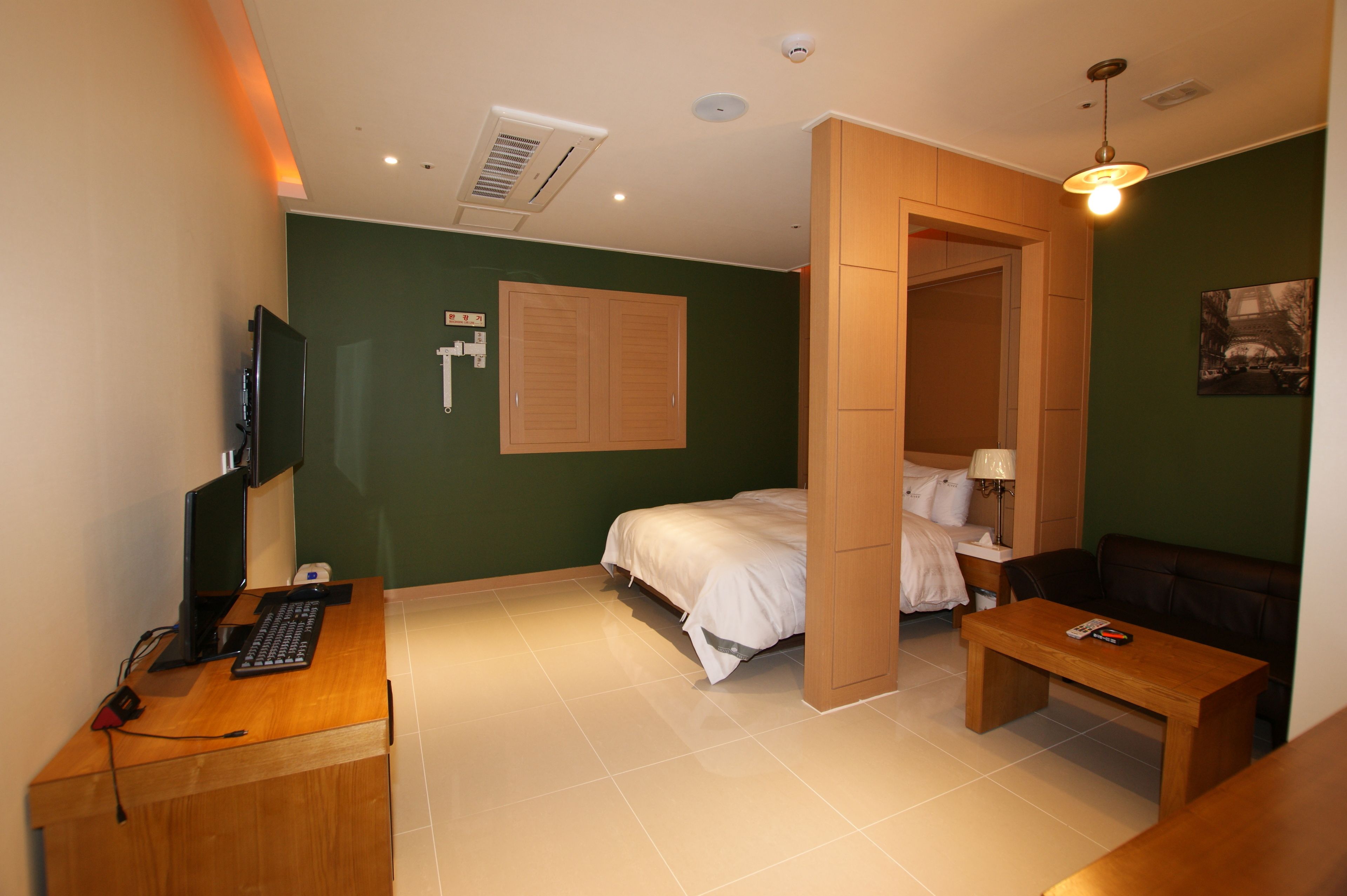Une chambre d’hôtel équipée d’un lit, d’un bureau avec un ordinateur, d’une chaise, d’un canapé et d’une télévision.