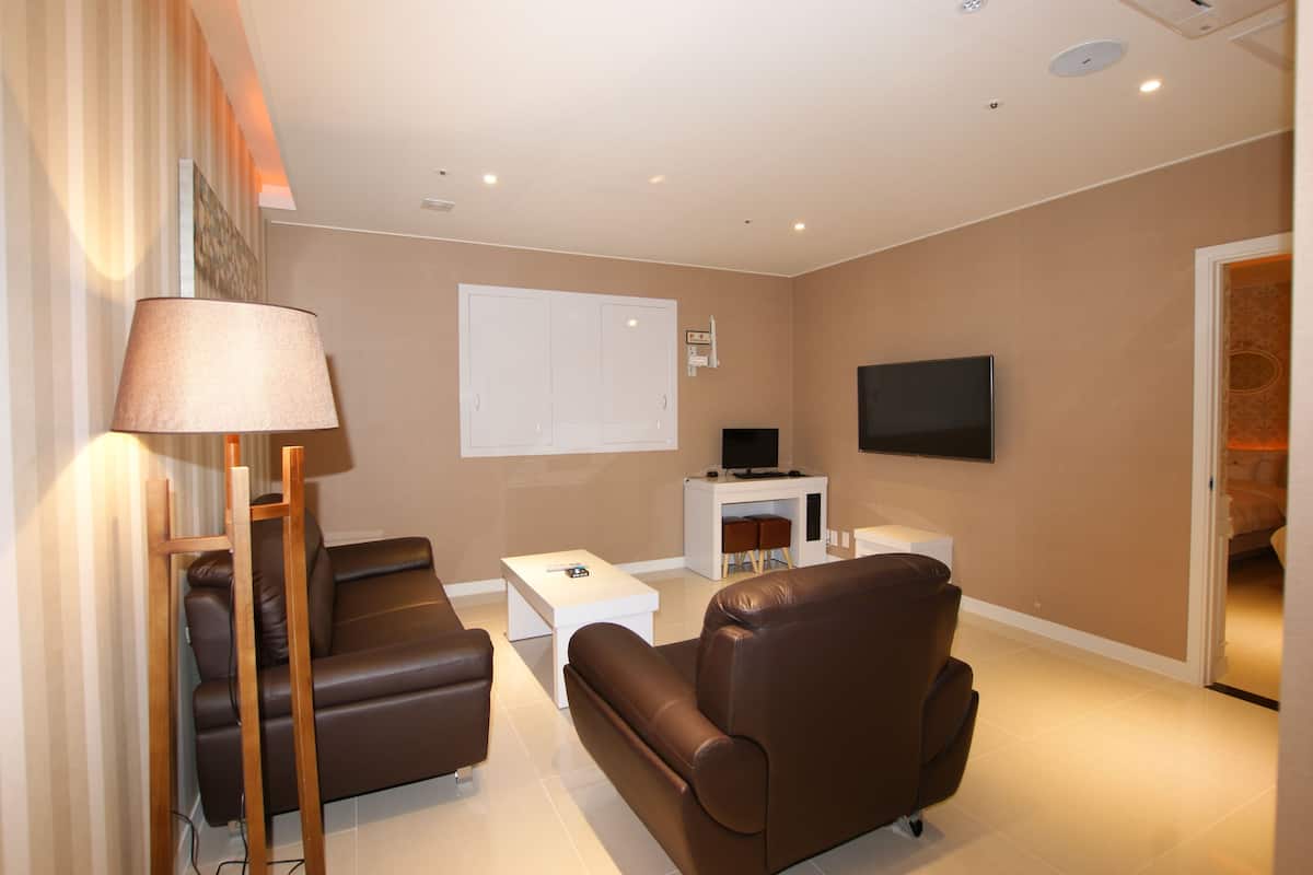 A modern living room with a sofa, coffee table, TV, and fireplace.