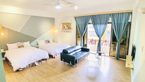 A hotel room with two beds, a sofa, a small table, and a balcony with a railing. - Snail Pets Homestay (Tainan)