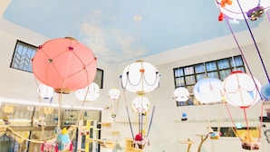 A room with a high ceiling decorated with hanging lanterns and a glass display case with toys. - Snail Pets Homestay (Tainan)