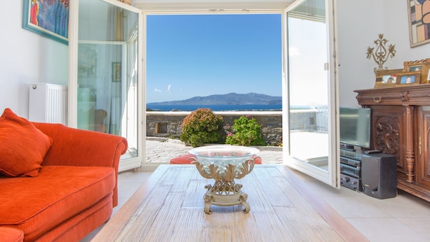 An open living room with a sofa, a glass coffee table, and a view of the sea. - villa victor 2 (Naxos)