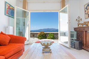 An open living room with a sofa, a glass coffee table, and a view of the sea. - villa victor 2 (Naxos)