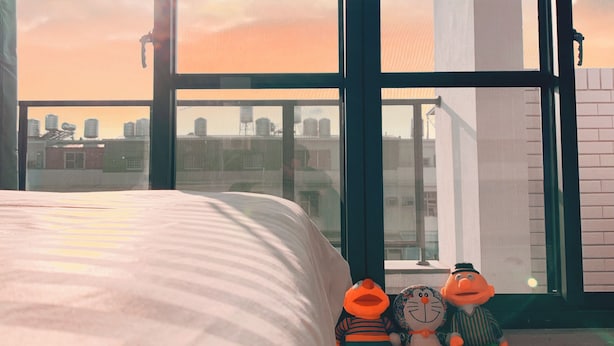 A bedroom with a large window, a bed, and two plush toys on the floor. - Tainan Anping High Chill B&B (Tainan)