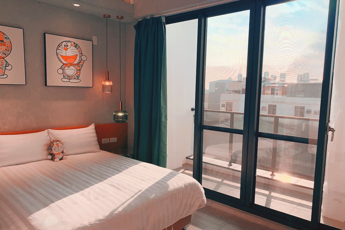 Une chambre avec un grand lit, une fenêtre avec des rideaux et des œuvres d’art accrochées au mur.