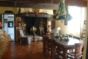 Un coin repas chaleureux avec une cheminée, des meubles en bois et une vue sur la cuisine.