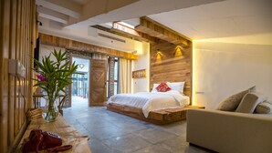 A modern bedroom with a bed, a sofa, and a wooden table with a vase and a telephone. - Maosao Inn (Zhangjiajie)