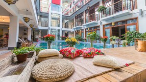 A multi-level atrium with wooden flooring, potted plants, and a central water feature. - Maosao Inn (Zhangjiajie)