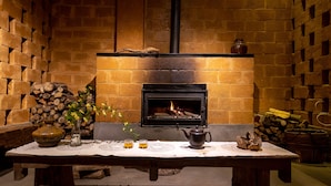 A cozy room with a brick fireplace, a table with a vase, candles, and a teapot. - Maosao Inn (Zhangjiajie)