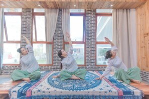 A room with large windows, a patterned rug, and a wooden ceiling.