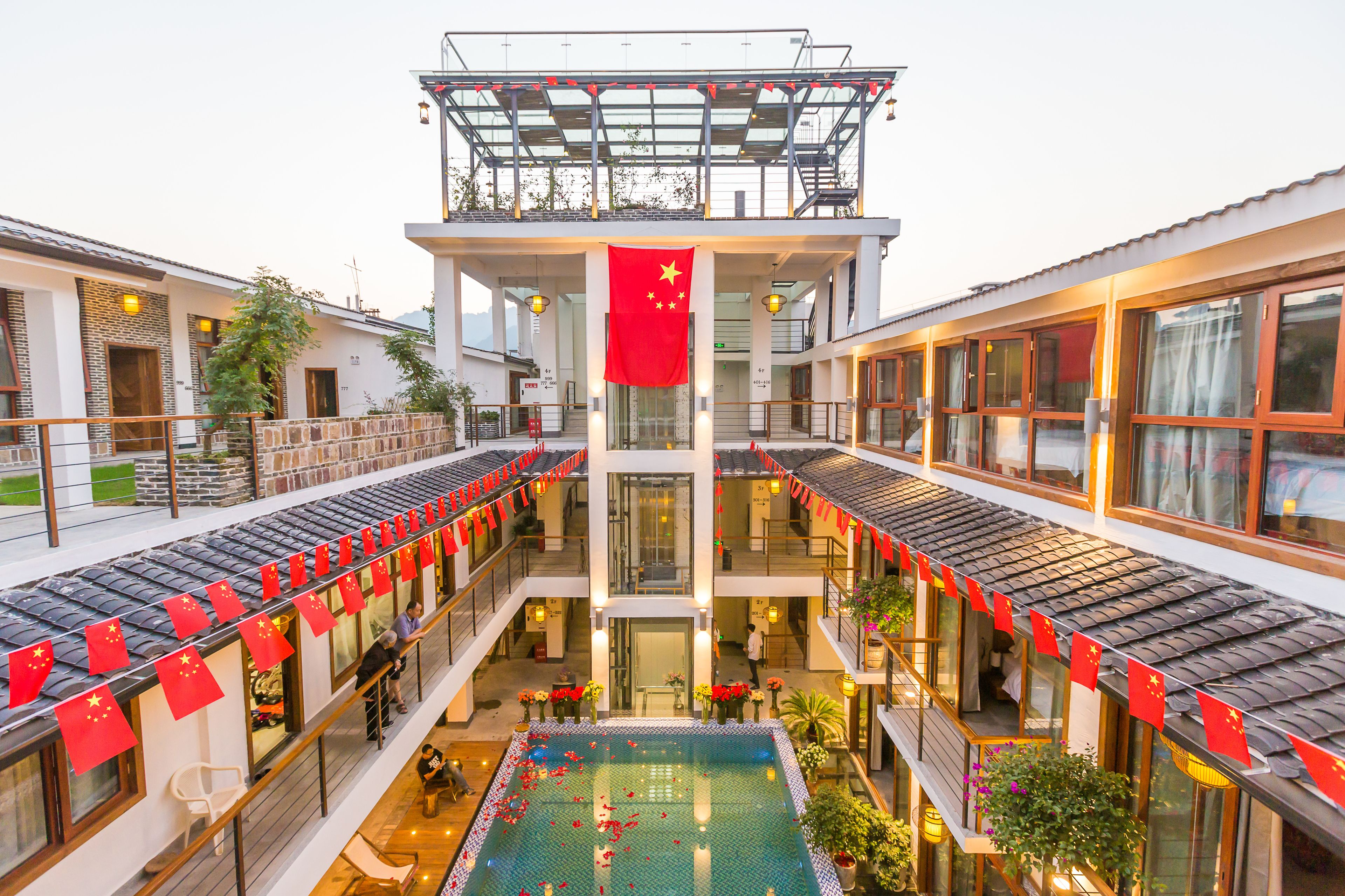 A multi-story hotel with a central atrium, a swimming pool, and red flags.