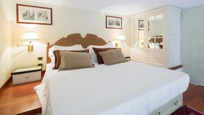A neatly arranged bedroom with a large bed, bedside lamps, a wardrobe, and framed pictures on the wall. - Old Tower Ponte Vecchio Suite A (Firenze)