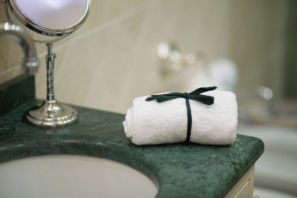 Un baño con encimera de mármol, un lavabo blanco y una toalla con un lazo verde.