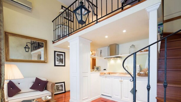 A spacious living area with a sofa, coffee table, and a staircase leading to an upper level. - Old Tower Ponte Vecchio Suite A (Firenze)