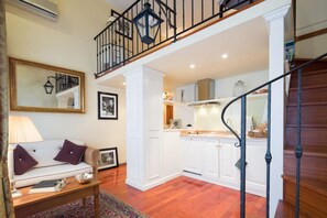 Amplia sala de estar con sofá, mesa de centro y una escalera que lleva a un nivel superior.