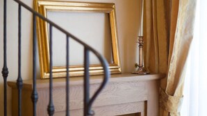 A staircase with a metal railing, a wooden console table with a framed picture, and a candle holder. - Old Tower Ponte Vecchio Suite A (Firenze)