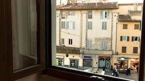 A window view of a street with buildings, shops, and pedestrians. - Oriuolo Palace Fantastic, brand-new apartment in the heart of Florence (Florence)