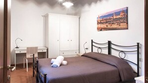 A bedroom with a bed, a desk, a wardrobe, and a cityscape painting on the wall. - Oriuolo Palace Fantastic, brand-new apartment in the heart of Florence (Florence)
