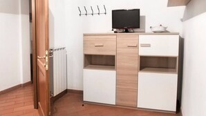 A room with a wooden cabinet, a television on top, and a radiator. - Oriuolo Palace Fantastic, brand-new apartment in the heart of Florence (Florence)
