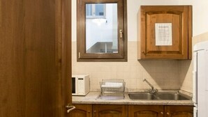 A kitchen with wooden cabinets, a microwave, a sink, and a window. - Oriuolo Palace Fantastic, brand-new apartment in the heart of Florence (Florence)