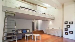 Amplia sala de estar con entrepiso, una escalera, un sofá y una mesa de centro.