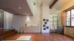 Un interior moderno con suelo de madera, una mesa blanca, un separador de vidrio y un radiador.