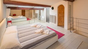 Un dormitorio con cama, alfombra roja, puerta de madera y balcón.