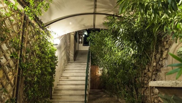 Una escalera con techo curvo, rodeada de vegetación exuberante y paredes de piedra.