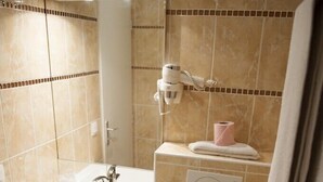 Un baño pequeño con lavamanos blanco, mueble oscuro y retrete.