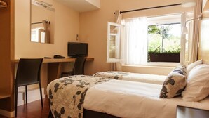 Un dormitorio con dos camas, un escritorio, una silla, un televisor y una ventana con cortinas.