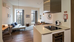 A modern kitchen with an island, built-in oven, and a dining area with a sofa and table.