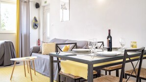 A dining area with a table set for two, a sofa, and a small stool. - Maslina Tree House (Hvar) - Peaceful retreat with garden & close to the sea (Stari Grad)