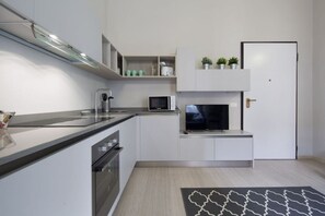 Una cocina compacta con microondas, horno y televisor sobre un mueble.