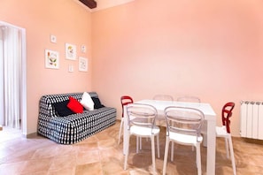 Una habitación con un sofá estampado, una mesa de comedor con sillas y obras de arte en la pared.