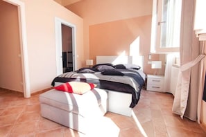 Un dormitorio con cama, mesitas de noche, un armario y una ventana.